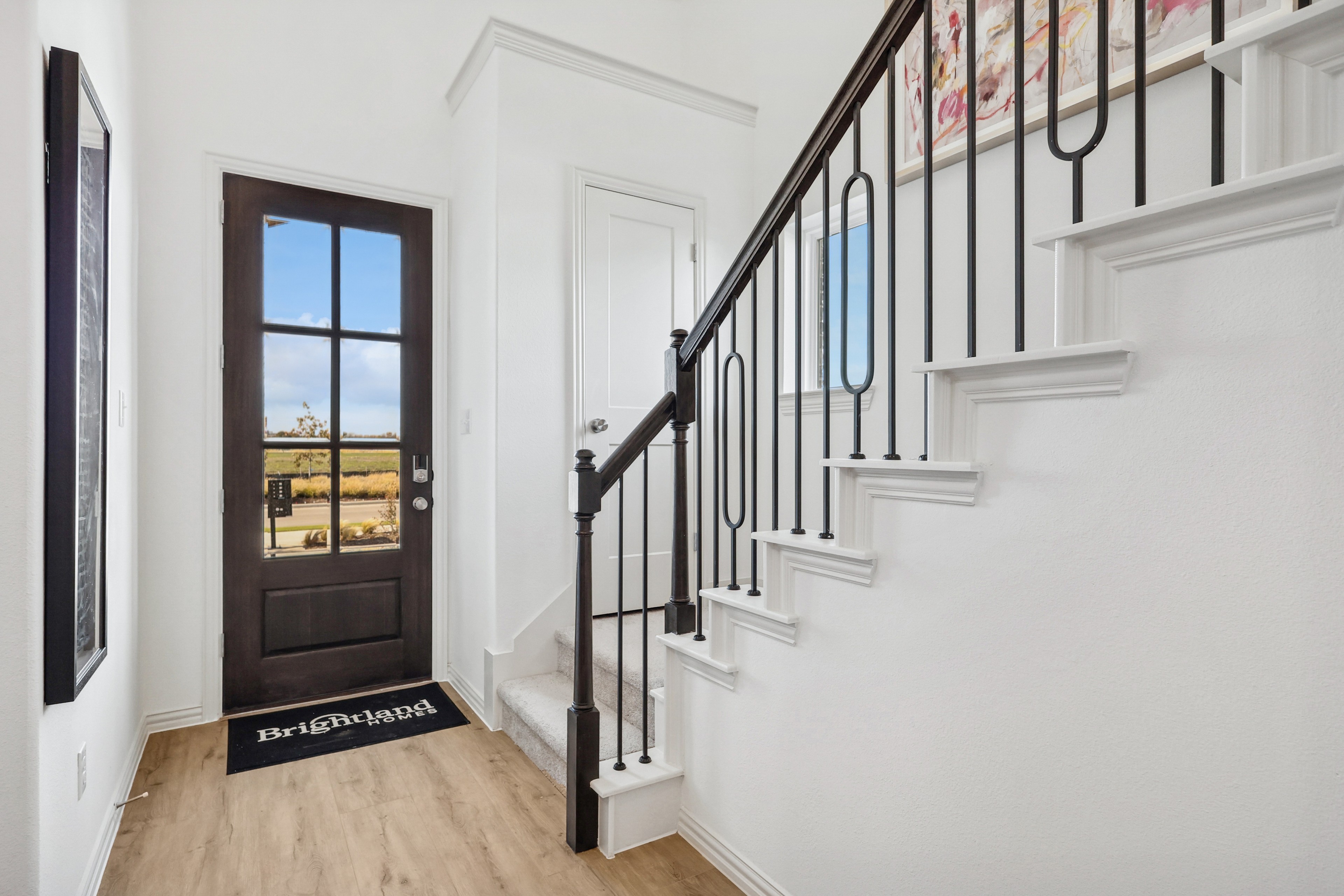 Bel Air Village Foyer with Stylish Door and Staircase Elegant Bel Air Village foyer with wooden floor, black-framed glass door, and chic staircase.