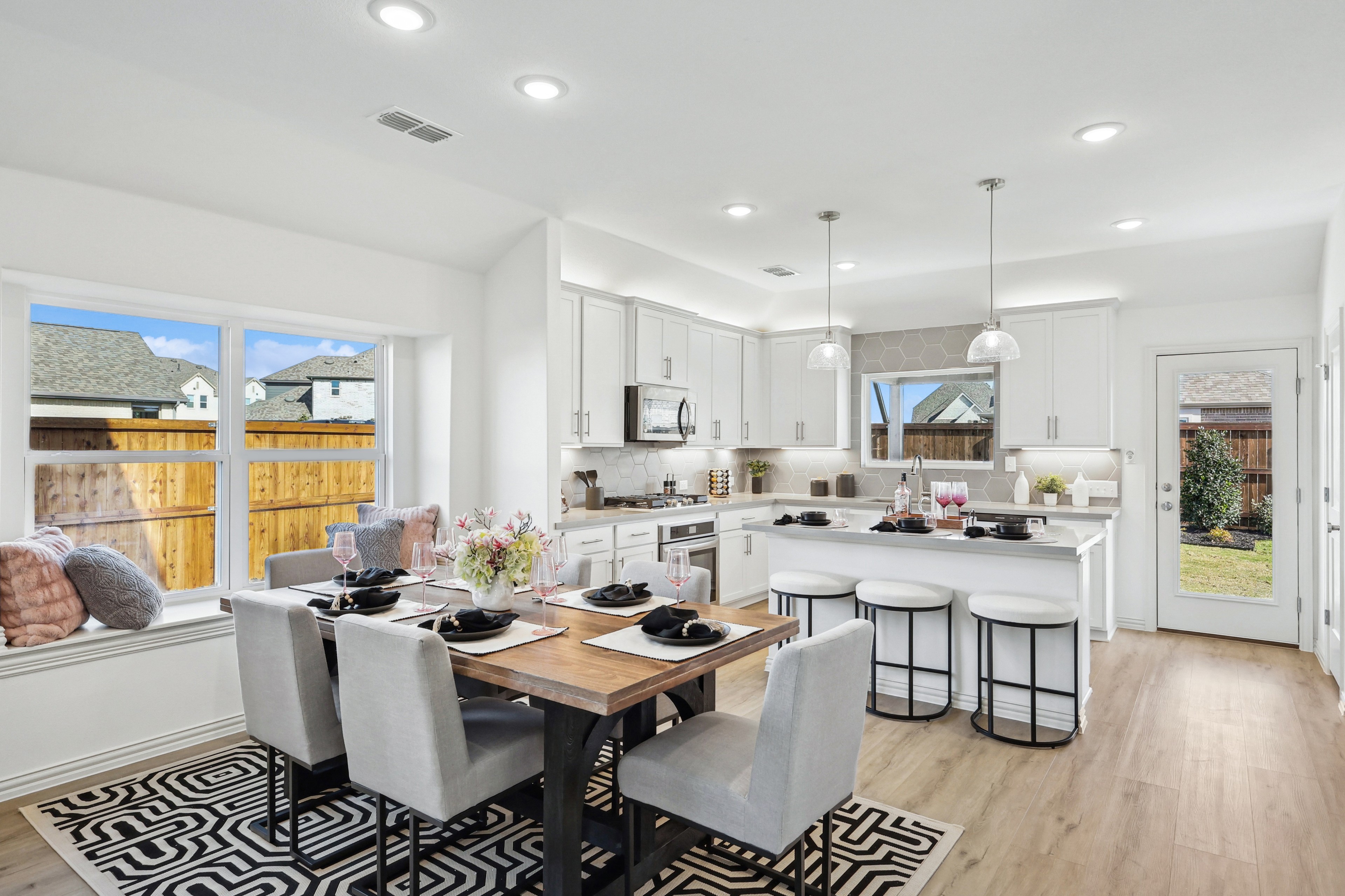 Modern Kitchen-Dining Area in Bel Air Village with Island Modern Bel Air Village kitchen-dining area with island, pendant lights, window seat, garden view.