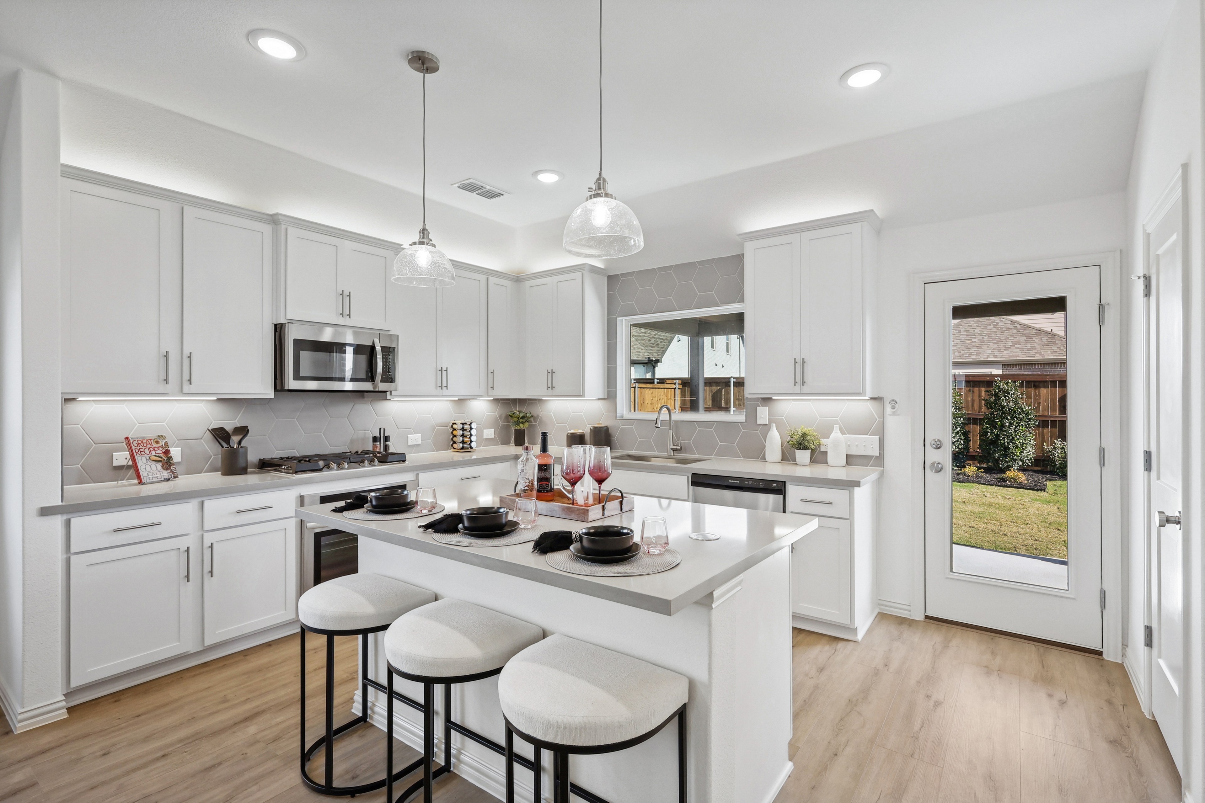 Modern Kitchen in Bel Air Village with Elegant Design Features Modern kitchen in Bel Air Village; white cabinets, hex tile backsplash, island with stools, glass pendant lights.