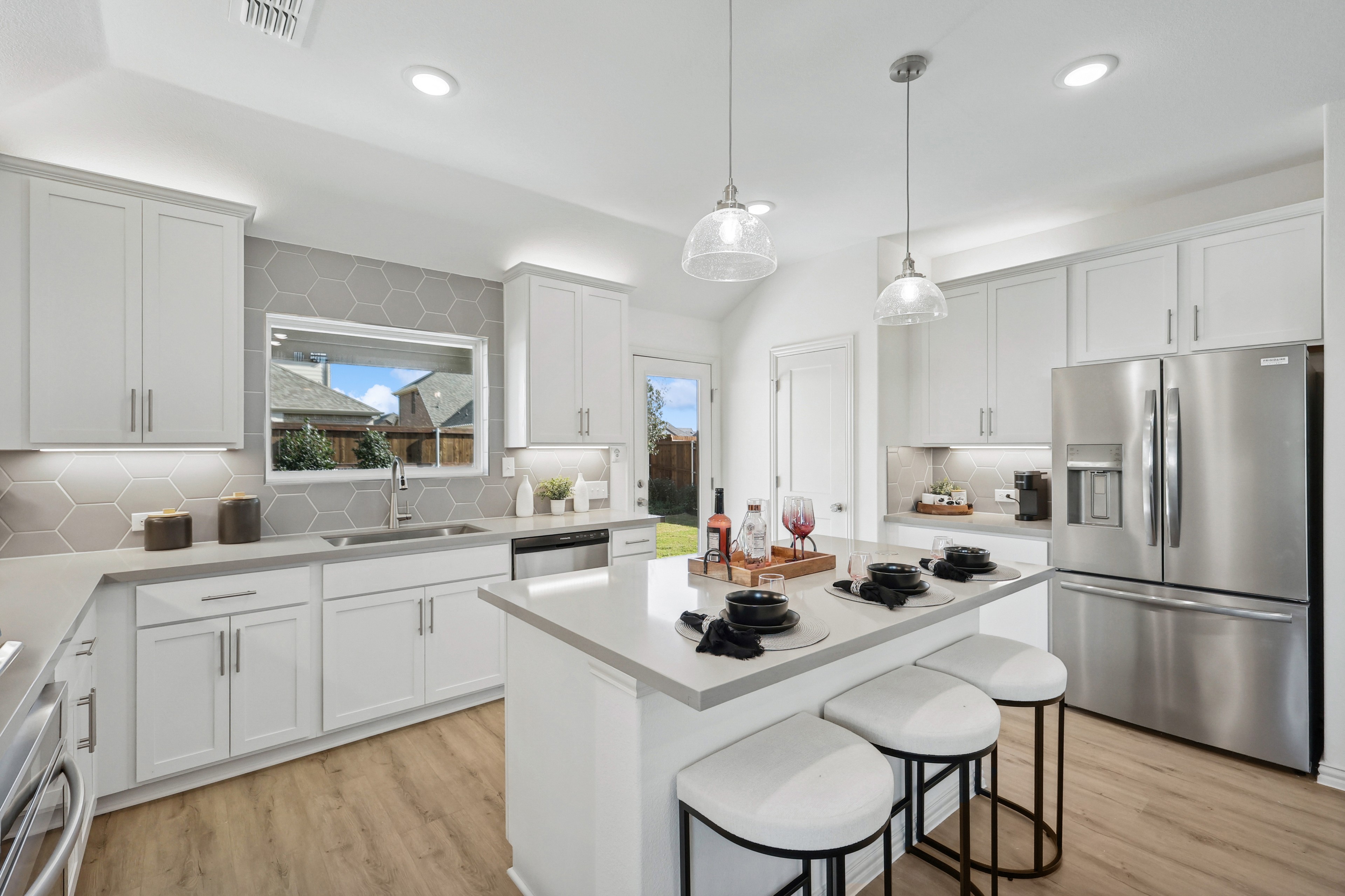 Elegant Kitchen in Bel Air Village with Modern Features Modern Bel Air Village kitchen with white cabinets, hex tile backsplash, island, pendant lights, stainless appliances.