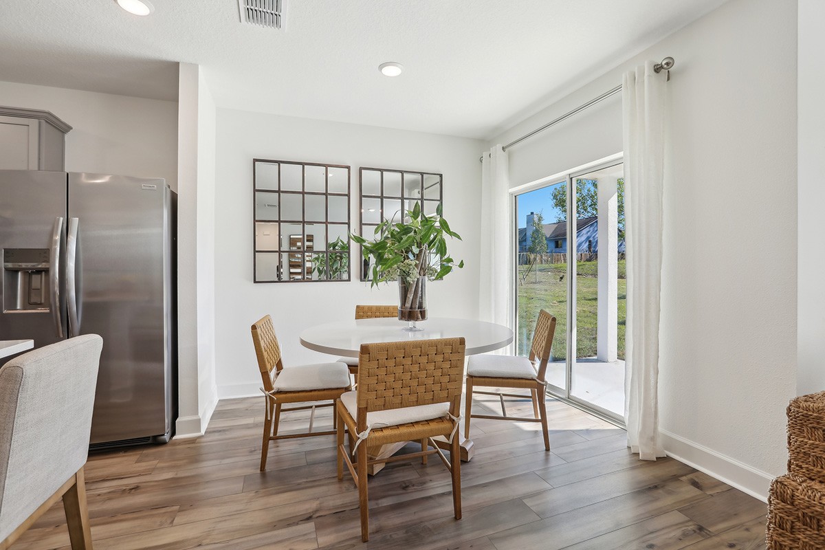 Elegant Dining Space with Natural Light in Spring Hill Home Dining area with round table, beige chairs, mirrors, and sliding glass doors in Spring Hill.
