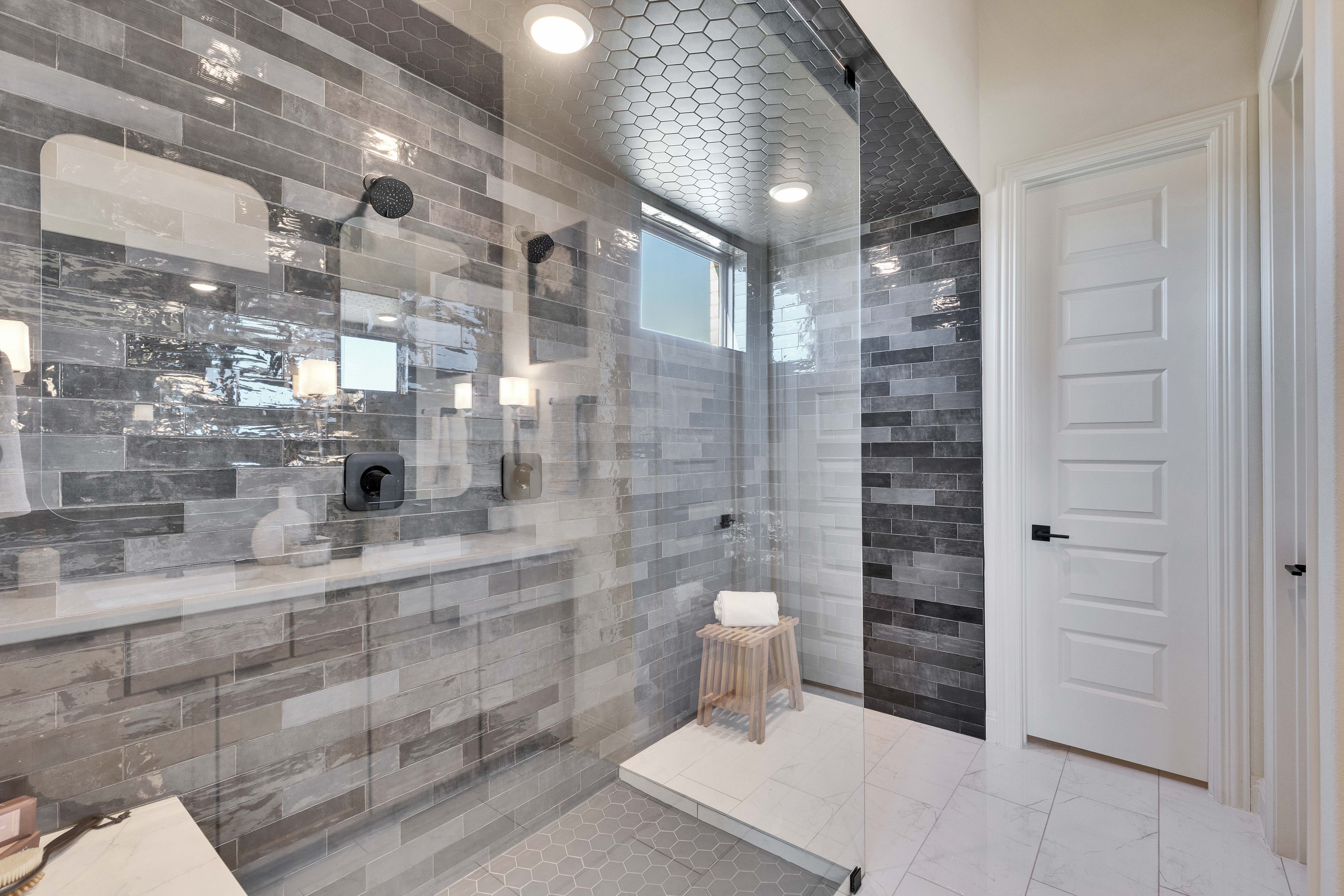 Luxurious Shower Design in Flora Community Luxury shower with glass walls, hexagonal tiles, sleek fixtures in Flora community. Modern design, elegant tones.