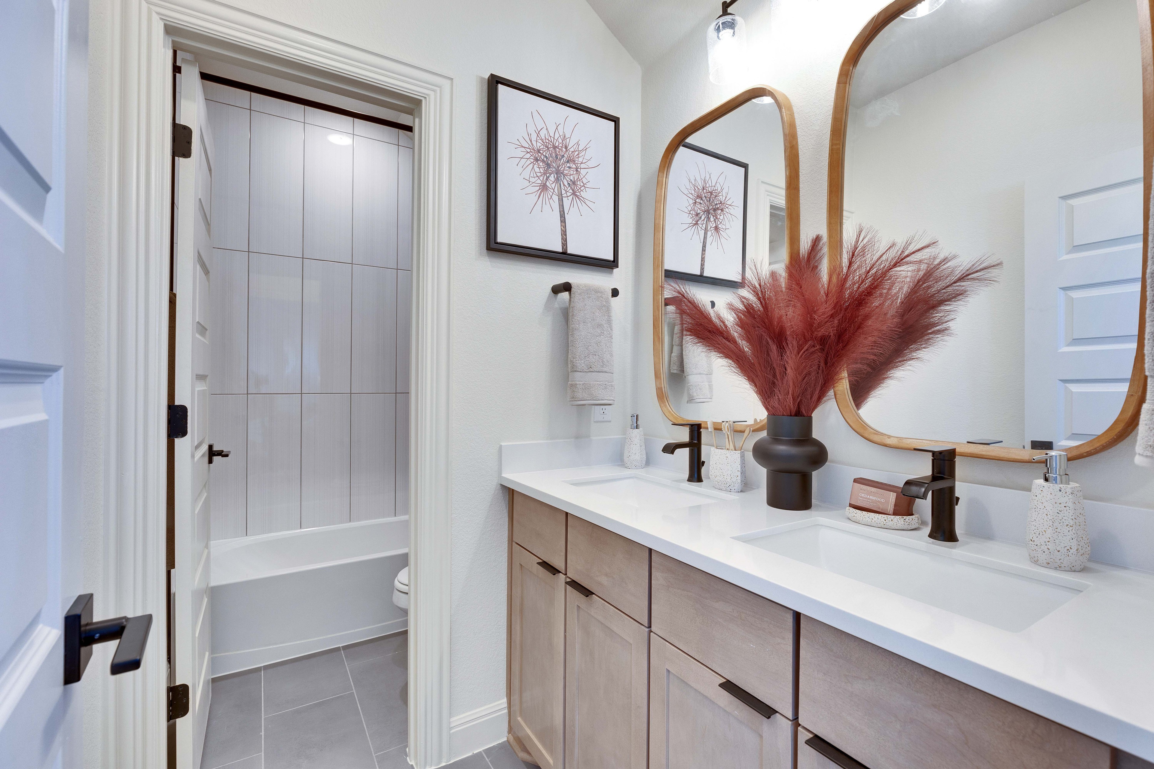 Twin Vanities in Flora Community Bathroom with Modern Fixtures Elegant bathroom with twin vanities, natural wood mirrors, modern faucets, art decor, located in Flora community.