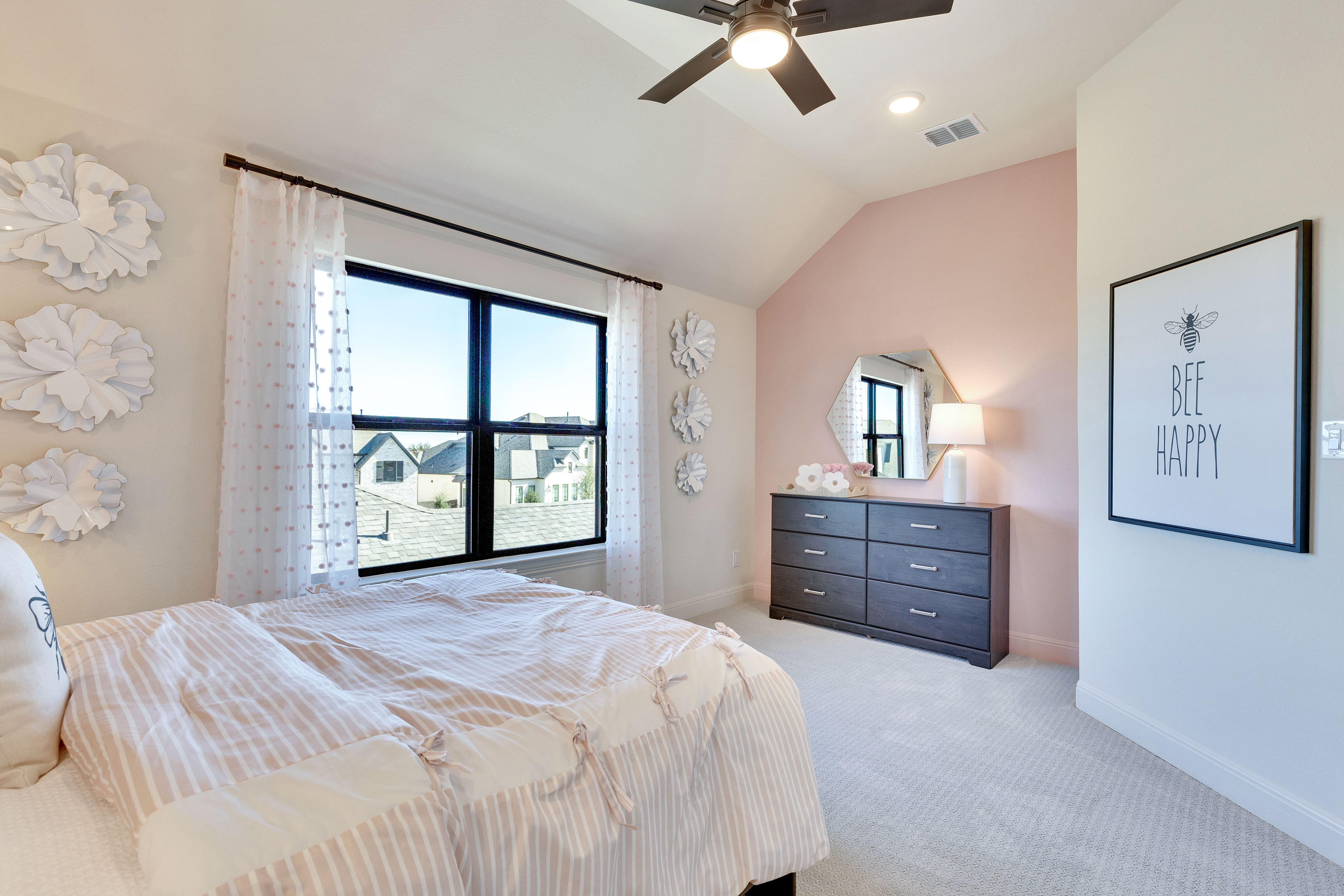 Sophisticated Bedroom Design with Pink Accents in Flora Community Elegant bedroom with pink accent wall, modern ceiling fan, large window, and sleek dresser.