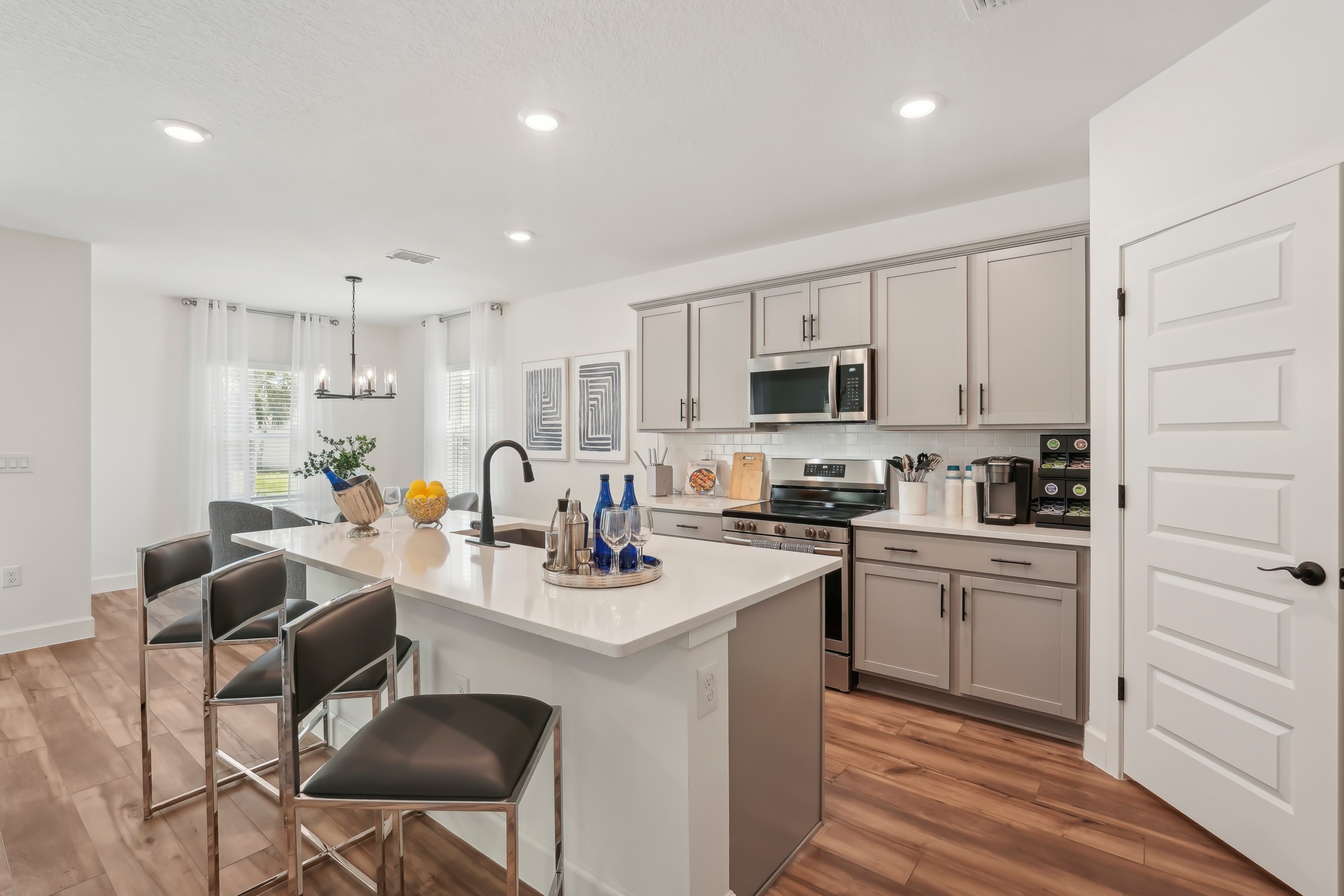 North Port Kitchen with Island and Stainless Appliances Modern North Port kitchen with white island, gray cabinets, stainless appliances, and wood floors.