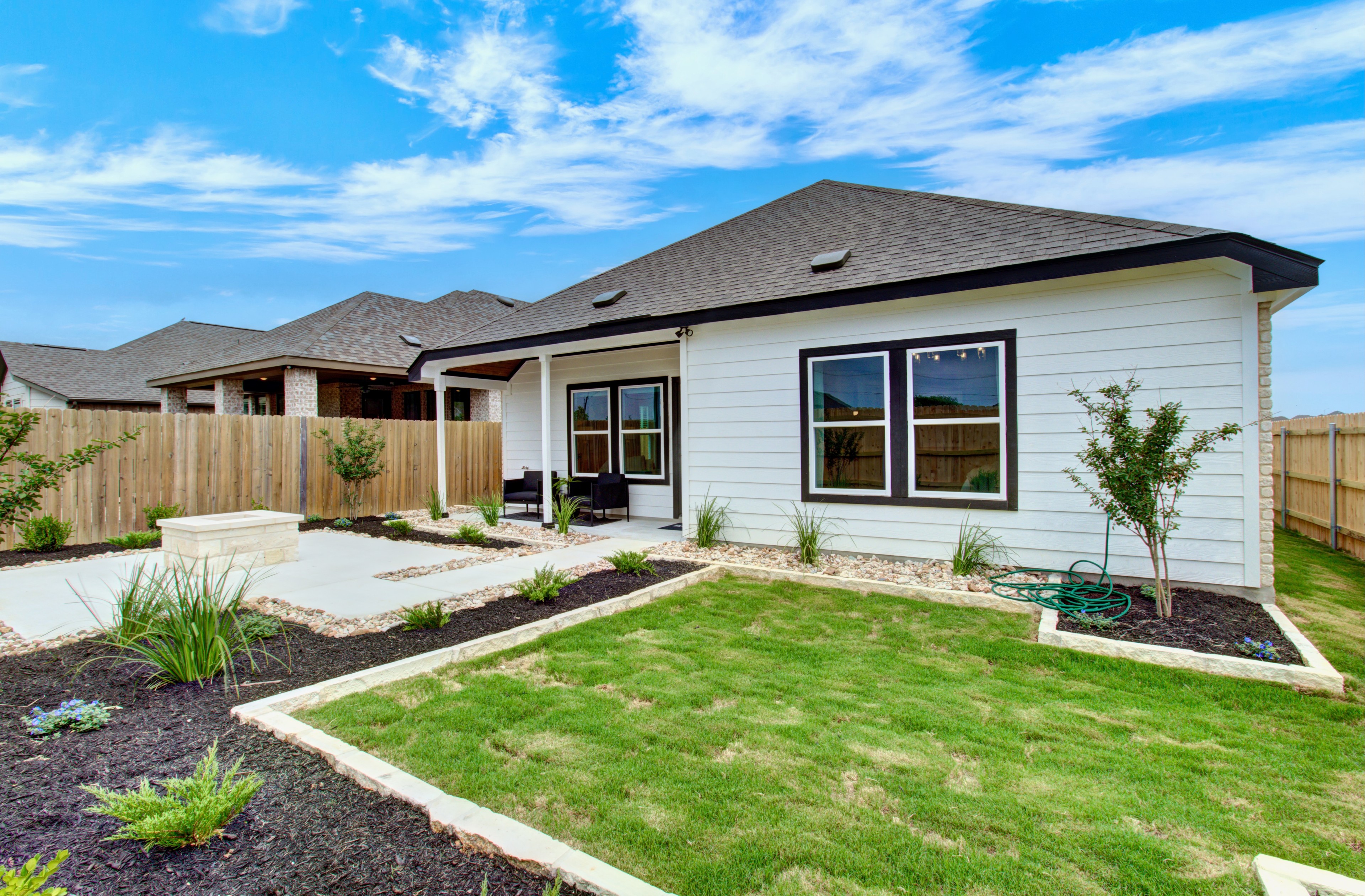 Sunflower Ridge Modern Backyard Patio with Garden Backyard with modern patio, garden, and white house in Sunflower Ridge community, featuring fenced privacy.