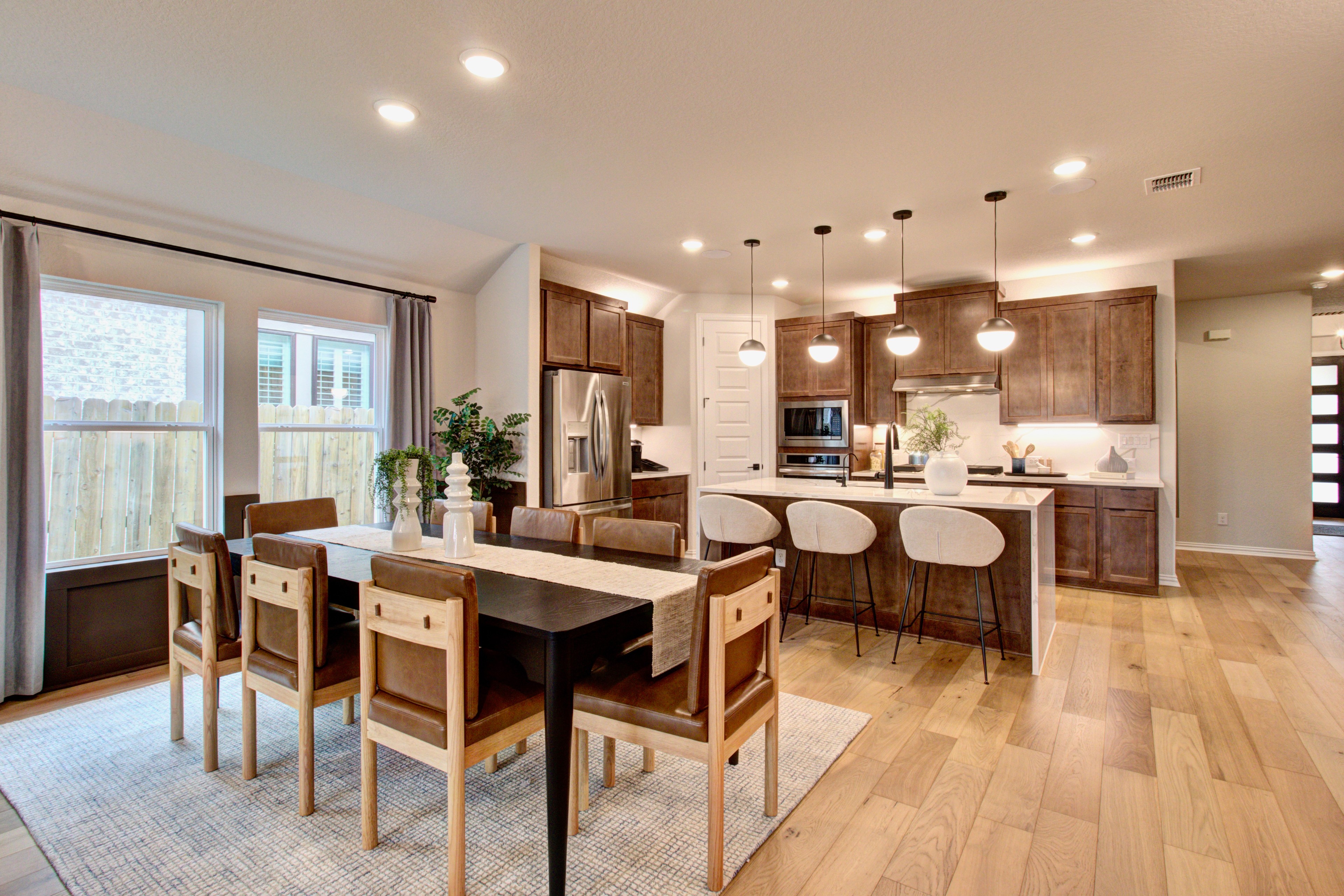 Sunflower Ridge Kitchen-Dining Area with Modern Interior Design Elegant kitchen-dining area in Sunflower Ridge; wood floors, modern lighting, brown cabinetry, large windows.