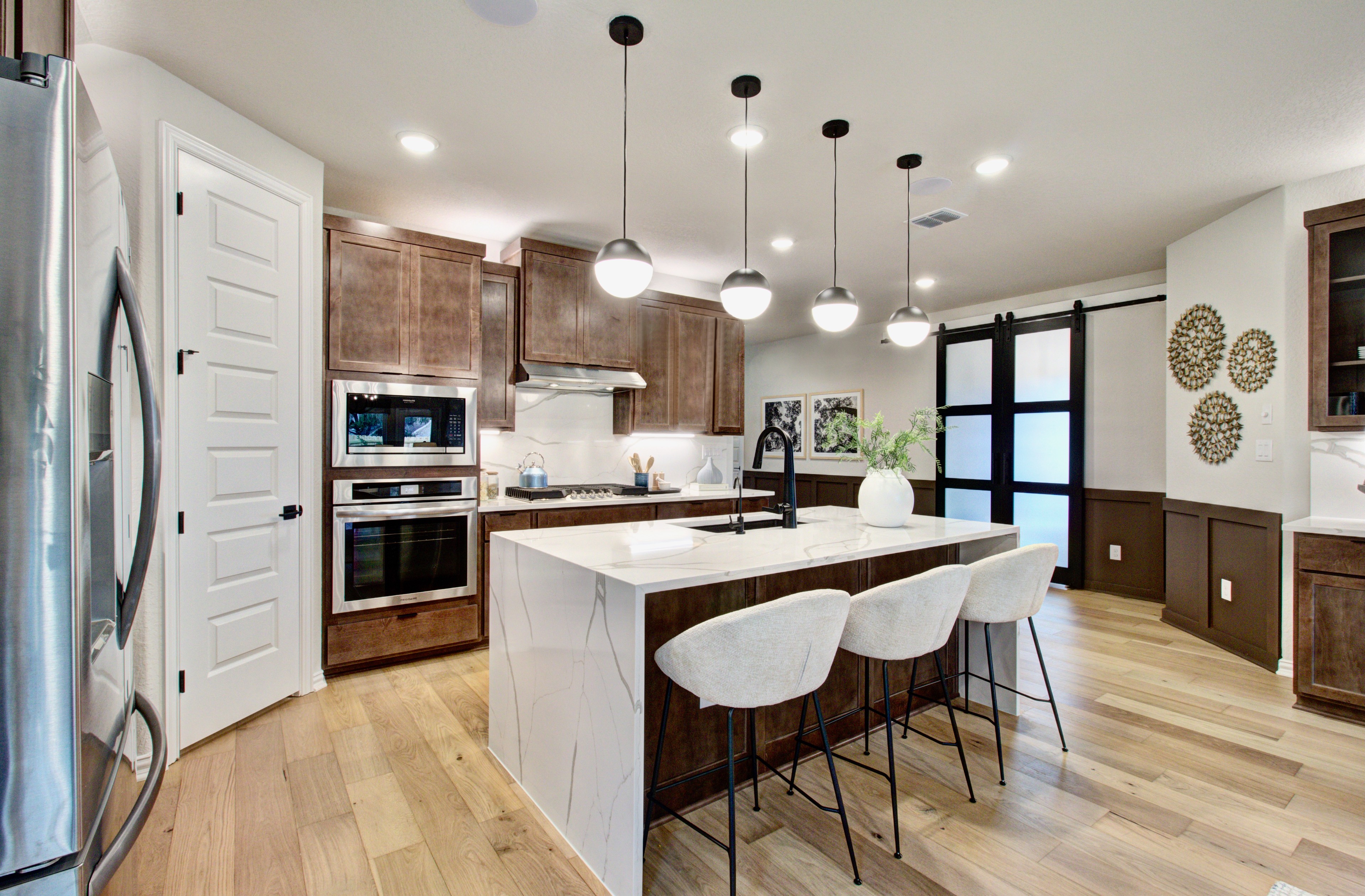 Modern Kitchen with Marble Island and Wood Cabinets in Sunflower Ridge Modern kitchen with marble island, pendant lights, wood cabinetry, and hardwood floors in Sunflower Ridge community.