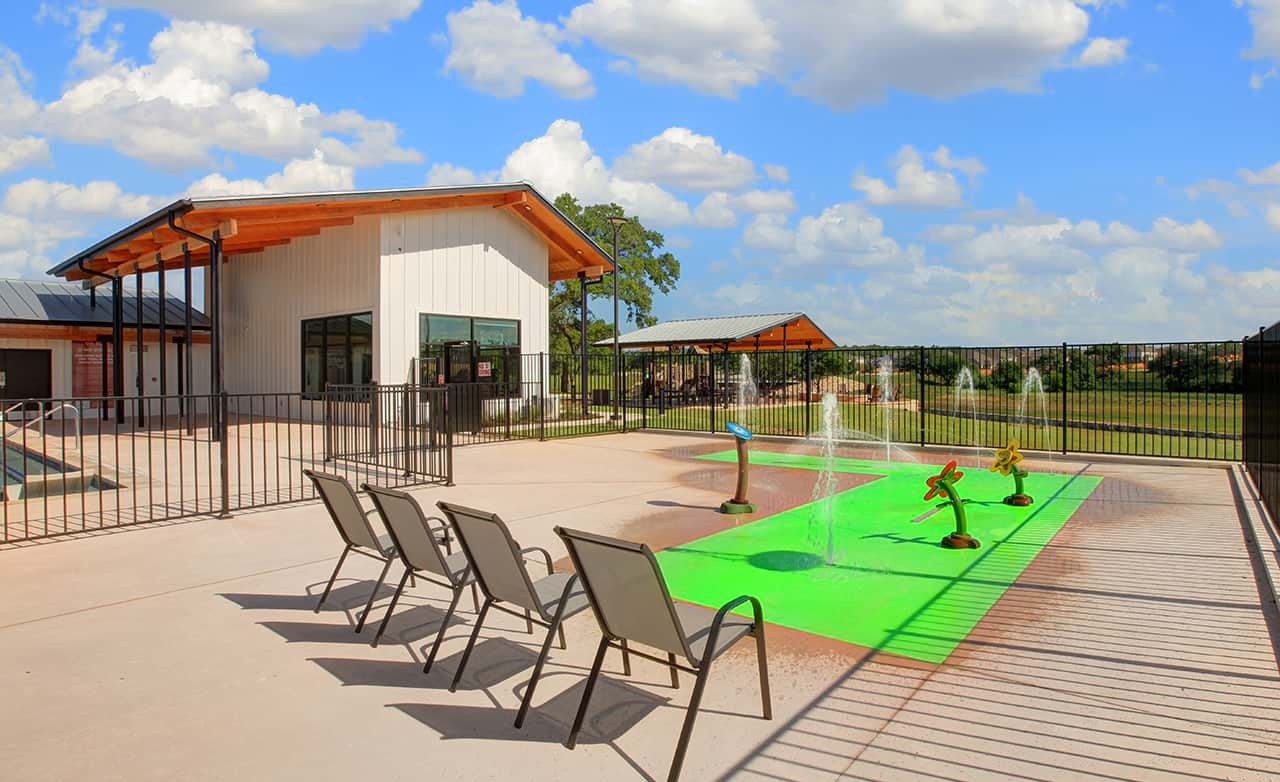 Enclave Community Meyer Ranch Pavilion with Splash Pad Meyer Ranch community center with modern pavilion, fenced area, splash pad, chairs; located in Enclave community.