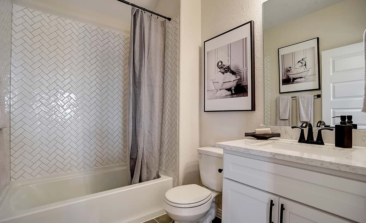 Luxurious Casinas at Gruene Bathroom with Herringbone Tile Bathroom with herringbone tile, marble vanity, stylish faucet, art at Casinas at Gruene community.