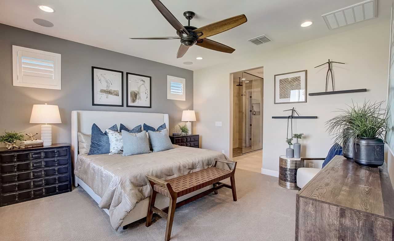 Modern Bedroom Design at Anderson Parc Featuring Chic Decor Elegant Anderson Parc bedroom with modern fan, wall art, neutral tones, and en-suite bathroom.
