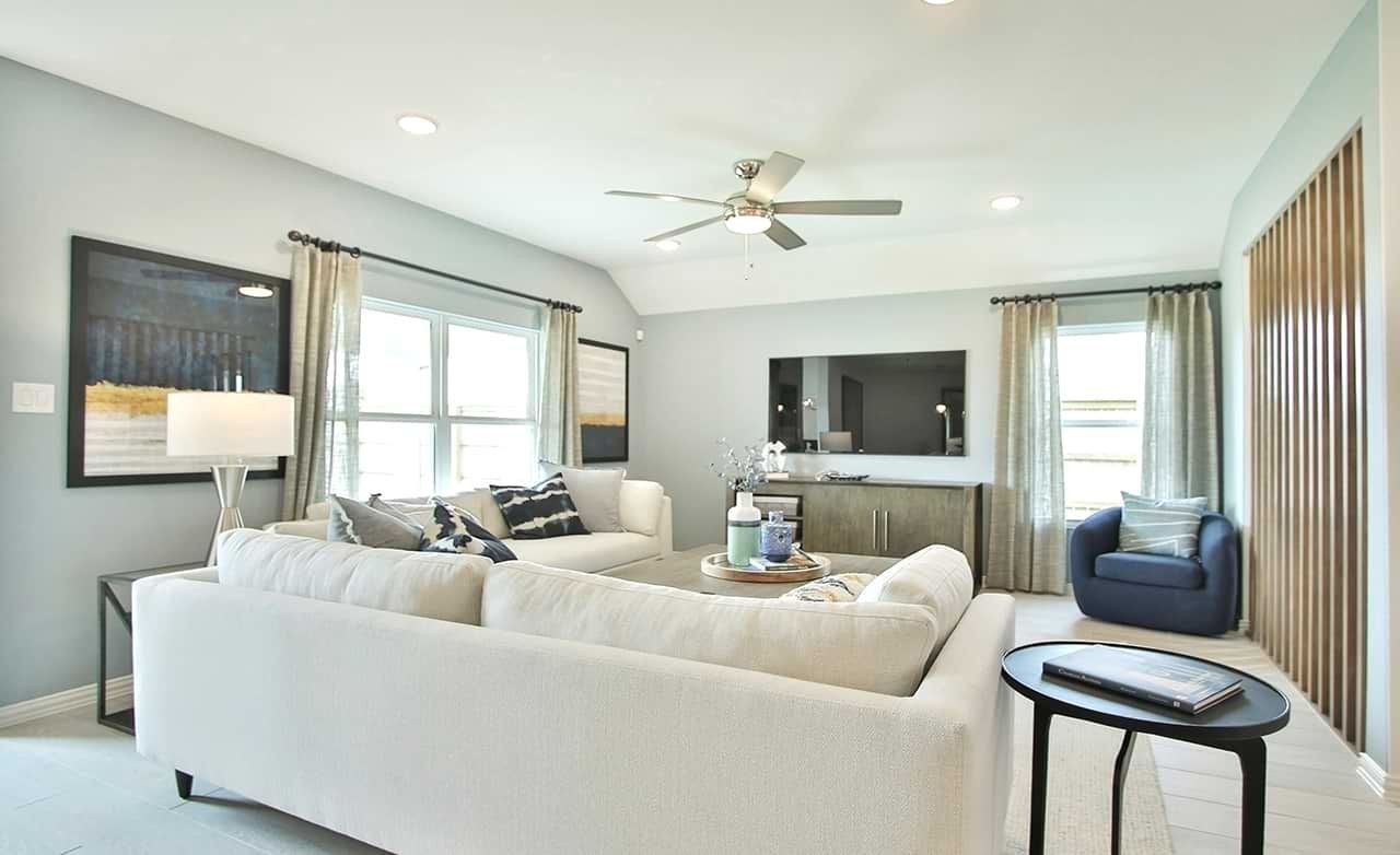 Oakwood Estates Living Room with Modern Decor and High-End Finishes Modern living room with neutral sofas, ceiling fan, artwork, in Oakwood Estates. Features wooden accents and ample lighting.