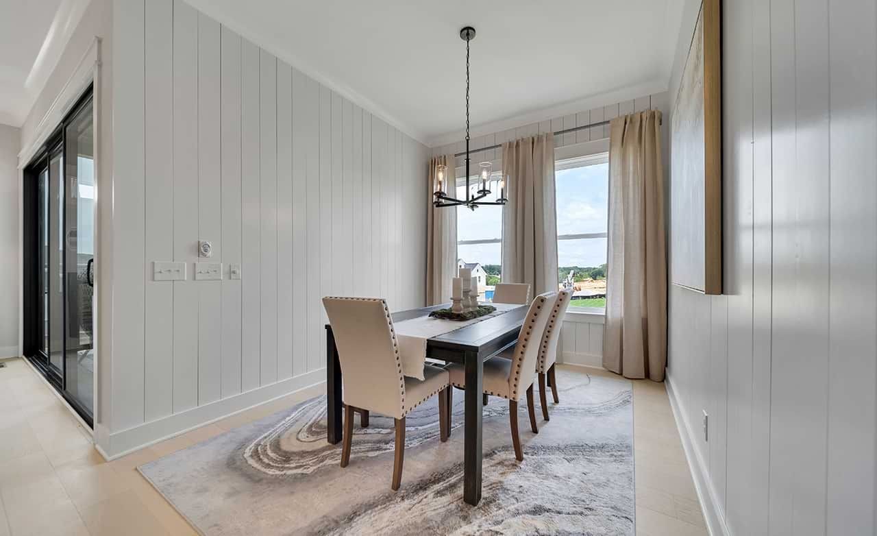 Luxurious Dining Room with Panel Walls at Richvale Estates Elegant dining room with panel walls, large window, luxury rug, modern chandelier. Richvale Estates setting.