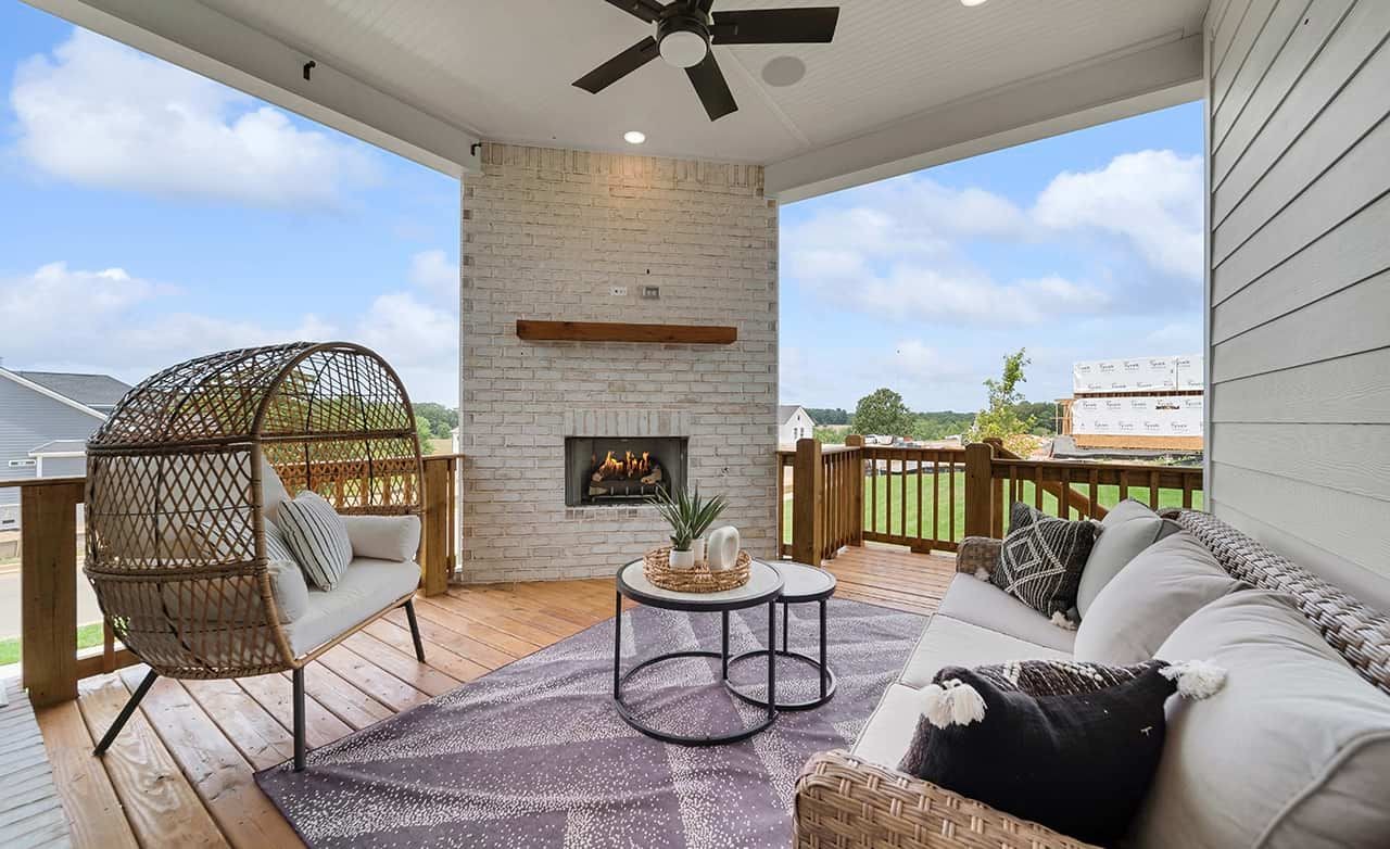 Richvale Estates Patio with Fireplace and Scenic View Elegant outdoor patio with wicker seating, brick fireplace, and scenic view at Richvale Estates.