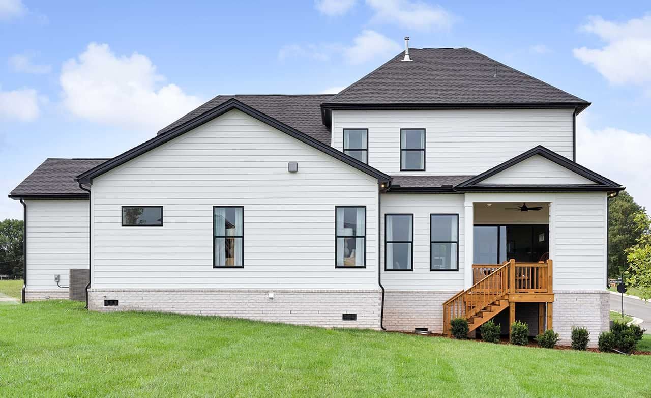 Modern White House with Gabled Roof in Richvale Estates Modern white house with black trim, large windows, gabled roof in Richvale Estates. Green lawn and blue sky.