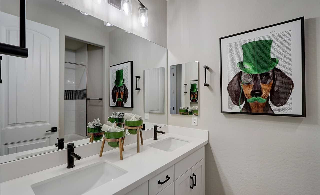 Luxurious Bathroom Design with Art in The Lakes at Rancho El Dorado Modern bathroom with dual sinks, sleek black fixtures, white cabinetry, dog artwork in The Lakes at Rancho El Dorado.