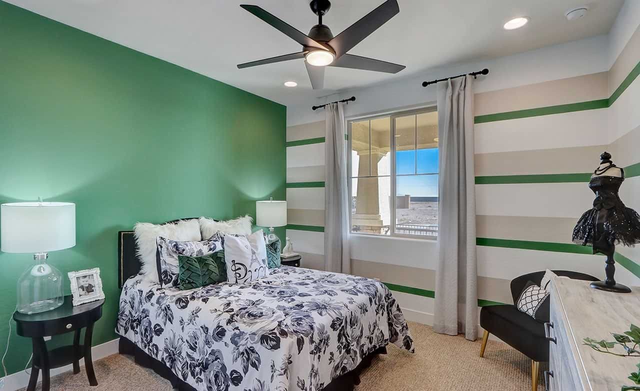 Elegant Bedroom Design at The Lakes at Rancho El Dorado Community Stylish bedroom with a green accent wall, modern ceiling fan, and striped drapes in The Lakes at Rancho El Dorado.