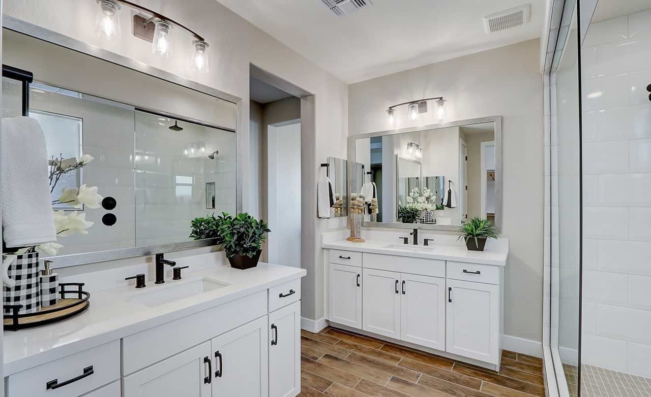 Luxurious Bathroom in Rancho El Dorado with Modern Amenities Elegant bathroom in Rancho El Dorado with dual sinks, large mirrors, and modern lighting. Features wooden tile flooring.