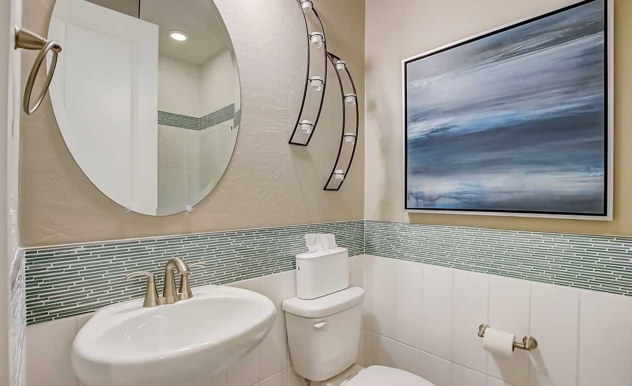 Luxury Bathroom Design at The Lakes, Rancho El Dorado Elegant bathroom with round mirror, modern fixtures, pastel tiles, abstract art at The Lakes, Rancho El Dorado.