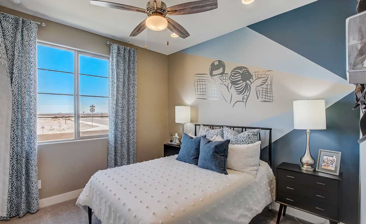Stylish Bedroom Design at Lakes at Rancho El Dorado Bedroom with patterned blue walls, large window, and ceiling fan; Lakes at Rancho El Dorado community.