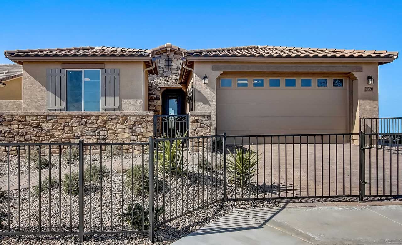 Ranch-style Home with Stone Facade in The Lakes at Rancho El Dorado Single-story home with stone facade, tile roof, and gated entrance at The Lakes at Rancho El Dorado.