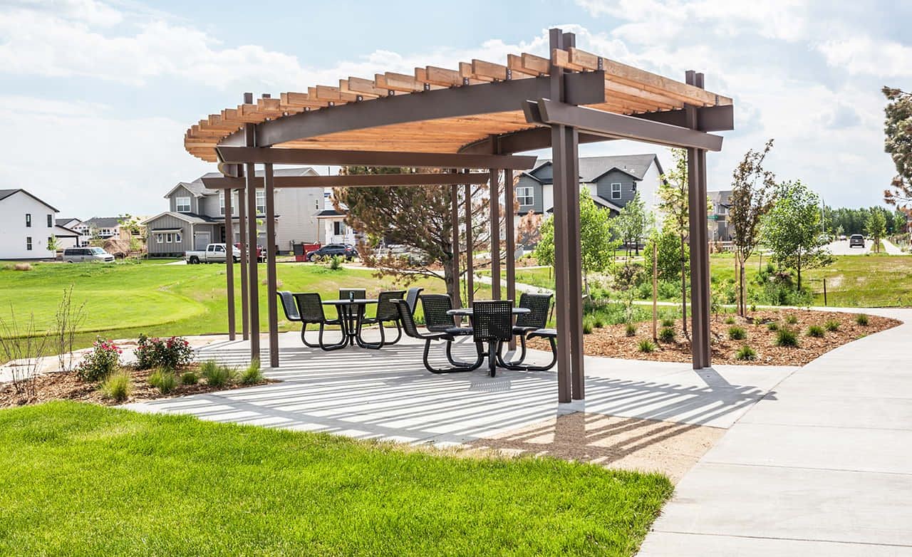 Wooden and Metal Pergola Seating in Trailside on Harmony Community Modern gazebo with wood and metal pergola, seating area, houses in background, Trailside on Harmony community.