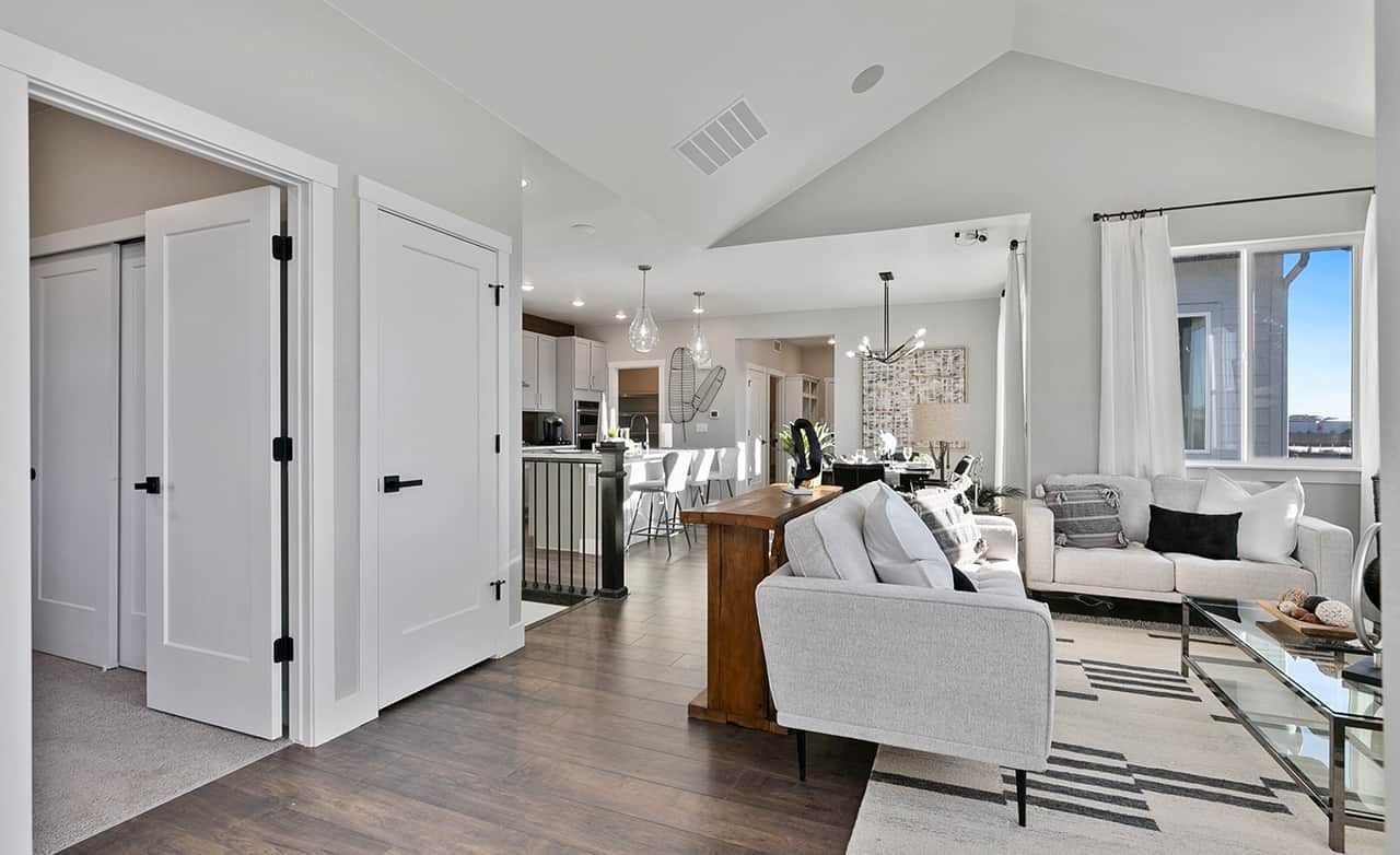 Modern Living Room with Vaulted Ceiling in Trailside on Harmony Modern living room with vaulted ceiling, hardwood floors, large windows, and pendant lighting in Trailside on Harmony.