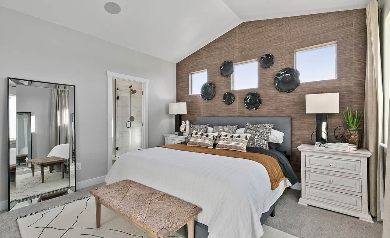 Luxury Bedroom Design in Trailside on Harmony with En-Suite Bath Modern bedroom with textured accent wall, elegant decor, and en-suite bathroom in Trailside on Harmony.