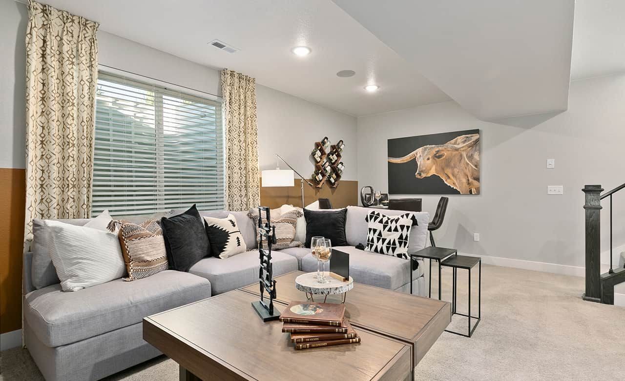 Luxurious Urban Living Room at Trailside on Harmony Modern living room with plush sectional, geometric pillows, large window, and bull art. Trailside on Harmony, urban home.