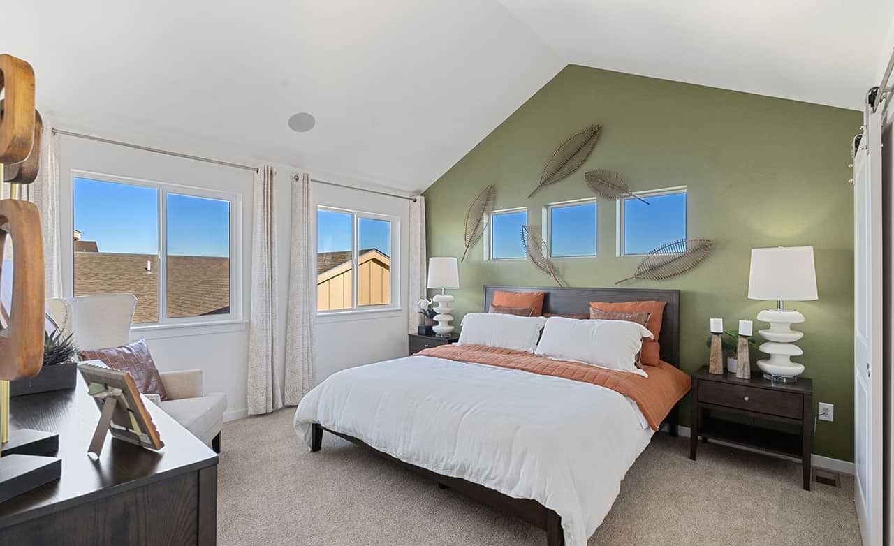 Luxury Bedroom with Vaulted Ceiling in Trailside on Harmony Elegant bedroom with vaulted ceiling, green accent wall, and modern decor in Trailside on Harmony community.