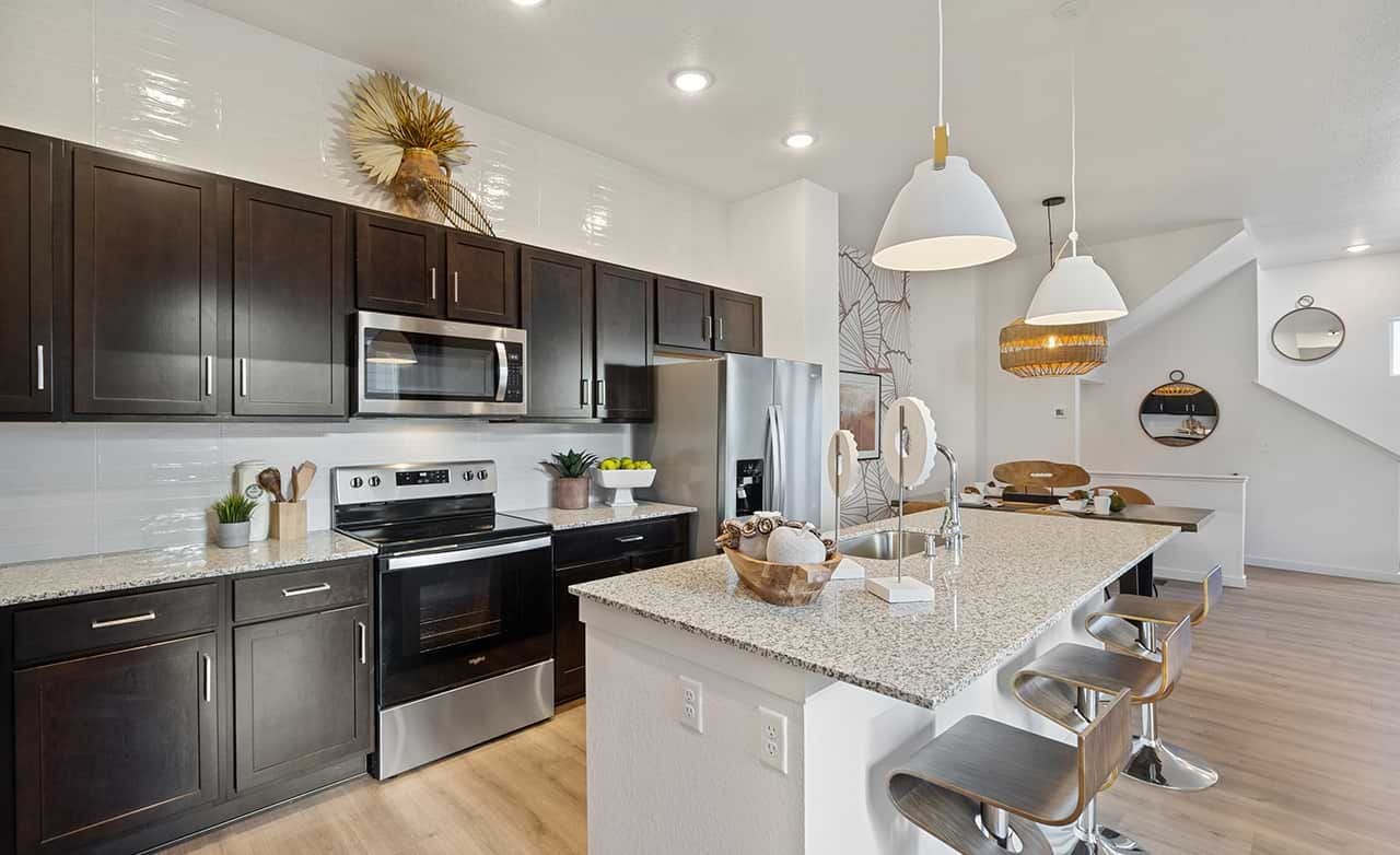 Modern Kitchen in Trailside on Harmony with Granite Countertops Modern kitchen with dark cabinets, granite countertops, pendant lights. Trailside on Harmony, stylish and elegant design.